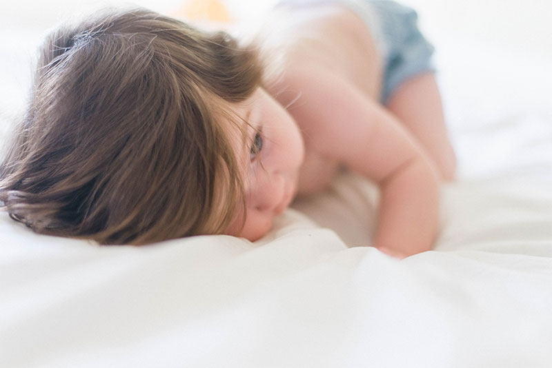 Child laying on white surface